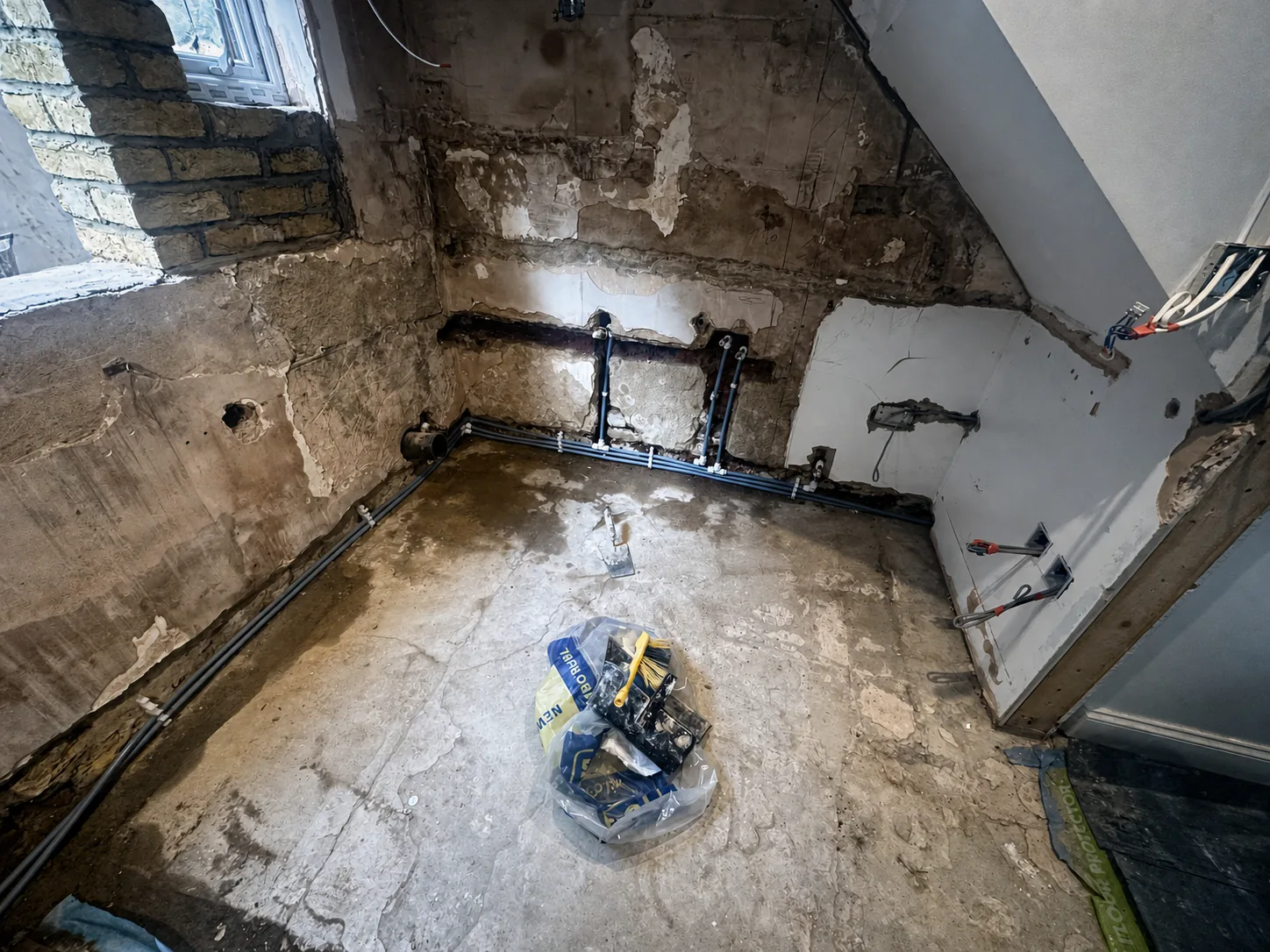 First-fix plumbing routed through a stripped kitchen and bathroom interior